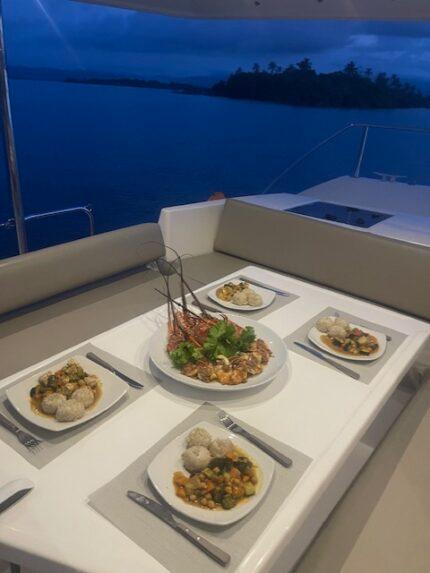 Plated seafood dinner served on deck at dusk
